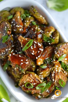 a white bowl filled with cooked brussel sprouts and sesame seeds