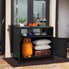 an open cabinet with luggage and wine glasses on the top, in front of a patio door