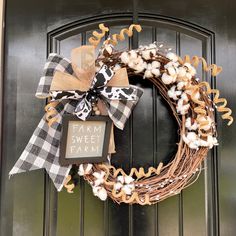 a wreath with a sign that says farm sweet farm hanging on the front door,