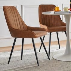 two chairs sitting at a table with food and drinks on top of it in front of a white wall