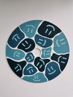 a blue and black circular object with white letters on it's center circle, surrounded by smaller circles that appear to be painted in different colors