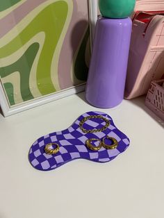 there is a purple and white checkered table cloth with rings on it next to a vase