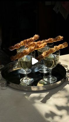 three glasses of wine on a tray with bread sticks sticking out of the top one