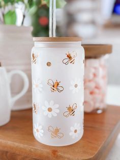 a glass jar sitting on top of a wooden table next to a cup with a straw in it