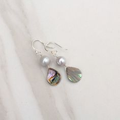 Los días de playa y los tacos van de la mano, y los aretes Abalone Shell Teardrop with Pearl son el accesorio perfecto para tal ocasión. Pero la elegancia atemporal de estas piezas clásicas de verano las hace adecuadas para una variedad de entornos, ya sea cerca de la playa o lejos. Esta pieza, que mide 1 5/8" (~40 mm) desde la parte superior del alambre de la oreja hasta la parte inferior de la concha, está disponible en su elección de plata de ley o bañada en oro. Con su belleza orgánica ún Summer Pieces, Paua Shell, Blue Pearl, Abalone Shell, Beach Days, Organic Beauty, Color Shades, Ear Wire, Pale Blue