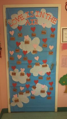 a door decorated with paper hearts and love is in the air written on it's side