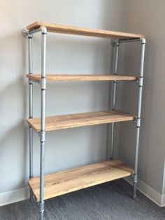 a three tiered shelving unit with metal pipes on the bottom and wood shelves