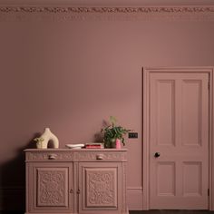 an empty room with pink walls and white furniture in the corner, painted in farrow