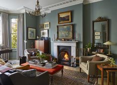 a living room filled with furniture and a fire place under a chandelier in front of a window