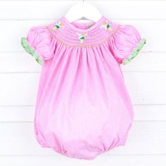 Experience enchanting moments with our Neverland Fairy Smocked Bubble. A perfect choice for playdates, birthdays, or your next magical theme park visit. This pink gingham bubble features our favorite green fairy smocked across the neckline. Adorable bishop sleeves with green gingham tape trim add a whimsical touch to this charming dress, ensuring it's perfect for your little one's memorable adventures. Features snaps in stride for easy dressing and diaper changes. Pink Puff Sleeve Smocked Dress For Garden Party, Pink Smocked Dress With Puff Sleeves For Garden Party, Playful Smocked Dress For Spring Playdate, Cute Pink Bubble Romper With Smocked Bodice, Cute Pink Bubble Romper With Smocked Back, Pink Smocked Dress For Playtime In Summer, Playful Pink Smocked Dress, Pink Smocked Dress For Summer Playtime, Cute Gingham Smocked Dress With Ruffles