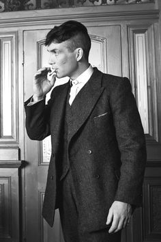 black and white photograph of man in suit brushing his teeth with an electric toothbrush