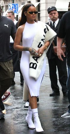 a woman in a white dress is walking down the street