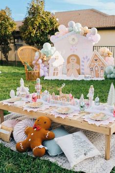 a table set up for a baby's first birthday with gingerbread house decorations