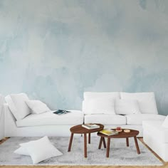 a living room filled with white furniture next to a wall painted in shades of blue