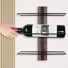 a hand is reaching for a bottle of wine on a wall shelf with three shelves