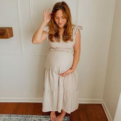 A solid maternity midi dress featuring smocked bust, self tie bow straps and tiered skirt. Skirt is double lined. Maternity Midi Dress Bump Friendly, Summer Beige Maternity Dress, Spring Maternity Dress Bump Friendly, Summer Maternity Dress In Beige, Summer Nursing-friendly Maternity Dress, Spring Sleeveless Bump Friendly Maternity Dress, Bump Friendly Sleeveless Maternity Dress For Spring, Spring Bump-friendly Maternity Dress, Spring Maternity Dress Midi Length