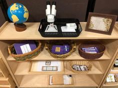 a book shelf with books and other items on it in front of a world globe