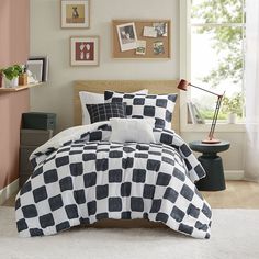 a black and white checkered comforter set on a bed in a room with pink walls