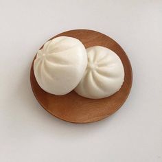 two pieces of food sitting on top of a wooden plate next to a white wall