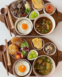 two trays filled with different types of food on top of a wooden serving platter