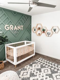 a baby's room with green walls and white crib in the corner, potted plants on the wall