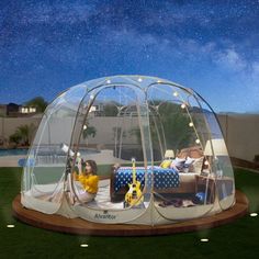 an inflatable tent is set up on top of a lawn with two children sitting inside