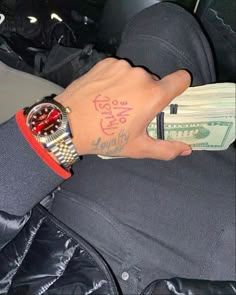 a person with a watch on their wrist and money in the other hand that is sitting next to him