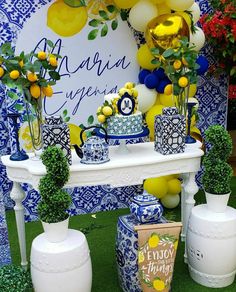 a table topped with vases filled with flowers and lemons next to a blue and white wall