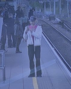 a man standing in front of a train station with his cell phone up to his ear