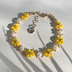 a yellow and white beaded bracelet on a white surface with shadow from the beads