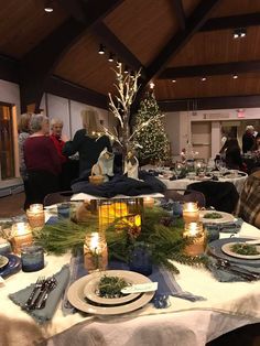 people are gathered around a table with plates and place settings on it for christmas dinner