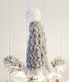 a knitted christmas ornament hanging from a tree with snow on it's branches