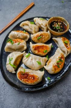 some dumplings are sitting on a plate with dipping sauce