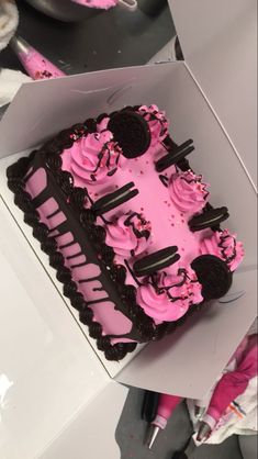 a birthday cake with pink frosting and oreo cookies on top in a box