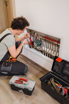 a man kneeling on the floor with tools in his hands