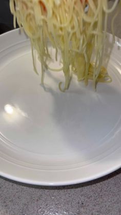 someone is sprinkling noodles on a white plate