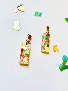 two pieces of glass sitting next to each other on a white surface with confetti scattered around them