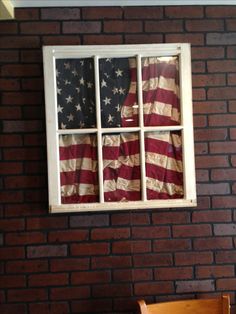 an american flag is seen through the window of a brick building with a bench in front of it