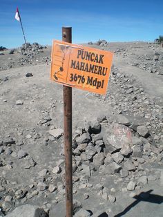 a sign that is sitting on the side of a pole in the middle of some rocks