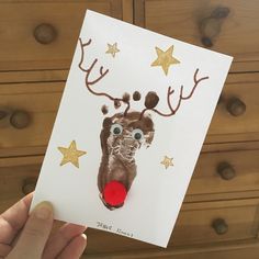 a hand holding up a card with a reindeer's face and stars on it