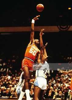 two men playing basketball in front of an audience at a sporting event during the 1970s