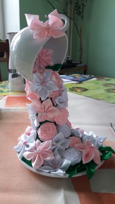 a white vase with pink and white flowers on it sitting on top of a table