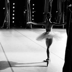 a black and white photo of a ballerina in the middle of a dance floor