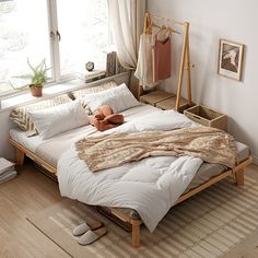 a bed sitting in a bedroom next to a window filled with pillows and blankets on top of it