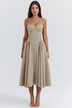 a woman is wearing a tan dress with straps on the waist and an open bust