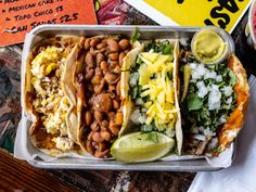 three tacos are in a tray on a table