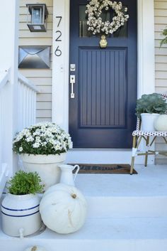 a blue front door with white flowers and potted plants