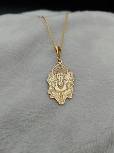 Celebrate spirituality and elegance with this exquisite Ganesha Necklace, crafted in 14K gold. This handmade piece features a delicate depiction of Lord Ganesh, making it a perfect religious charm necklace for those who cherish spiritual symbols. Its tiny and intricate design adds a subtle yet meaningful touch to any outfit, ideal for daily wear or special occasions. ⚜️ Package included: One Handmade Necklace ⚜️ Pendant Sizes: 14 / 16 / 18 / 20 / 22 / 24 / 26 / 28 / 30 mm ⚜️ Necklace Length: 14 / 16 / 18 / 20 / 22 inches ⚜️ Materials: 925 Sterling Silver / Gold Plated / 14K Solid Gold FAQ: ✈️ Express and Free Shipping. 📦 Items will be shipped within 1-2 business days. 🛒 Delivery times vary between 2-5 business days depending on the country of the order. 🔙 Return and exchange accepted wi Yellow Gold Filigree Jewelry For Puja, 22k Gold Jewelry For Navratri Gift, Pendant Temple Necklace With Filigree For Gifts, Pendant Temple Necklace With Filigree As A Gift, 22k Gold Temple Necklace For Navratri Gift, Gold Pendant Jewelry For Navratri, 22k Gold Temple Necklace With Intricate Design As Gift, Spiritual Yellow Gold Festive Jewelry, Spiritual Yellow Gold Jewelry For Festive Occasions