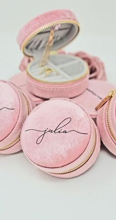 pink velvet jewelry cases with gold zippers and signature written on the inside, sitting on a white surface