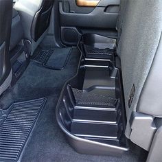 the interior of a vehicle with black floor mats and trays in place for various items